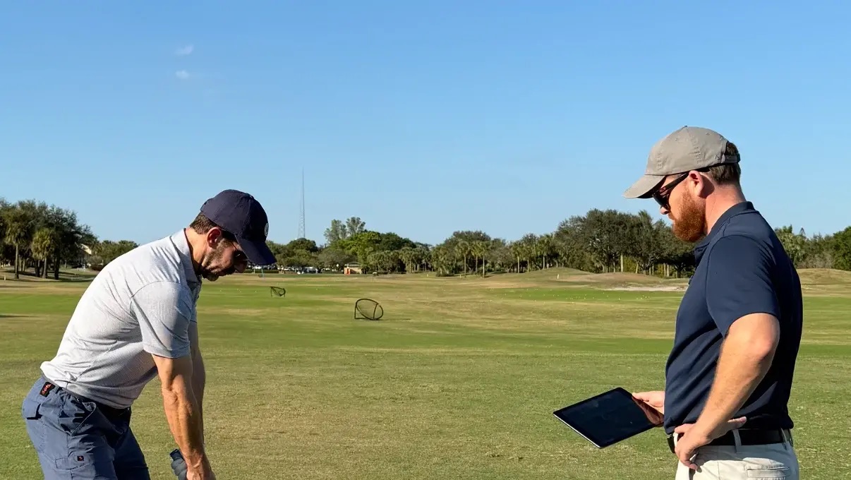 Duncan reviewing a student's swing on a tablet during a lesson on the range